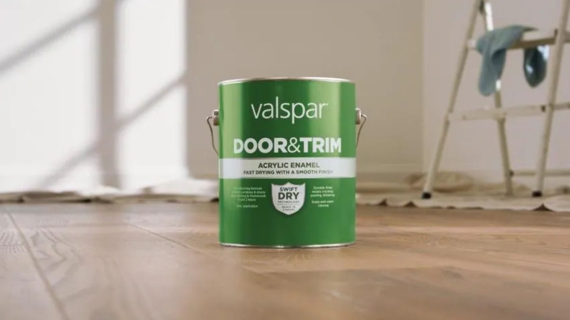 A can of Valspar door and trim paint sits on a wooden floor, showcasing its label and color options.