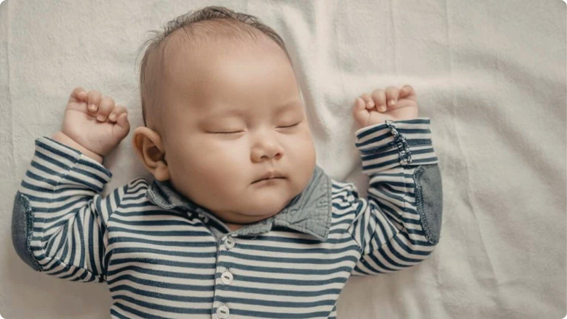 Peaceful baby sleeps without a pacifier in striped pajamas, showing success after night weaning.
