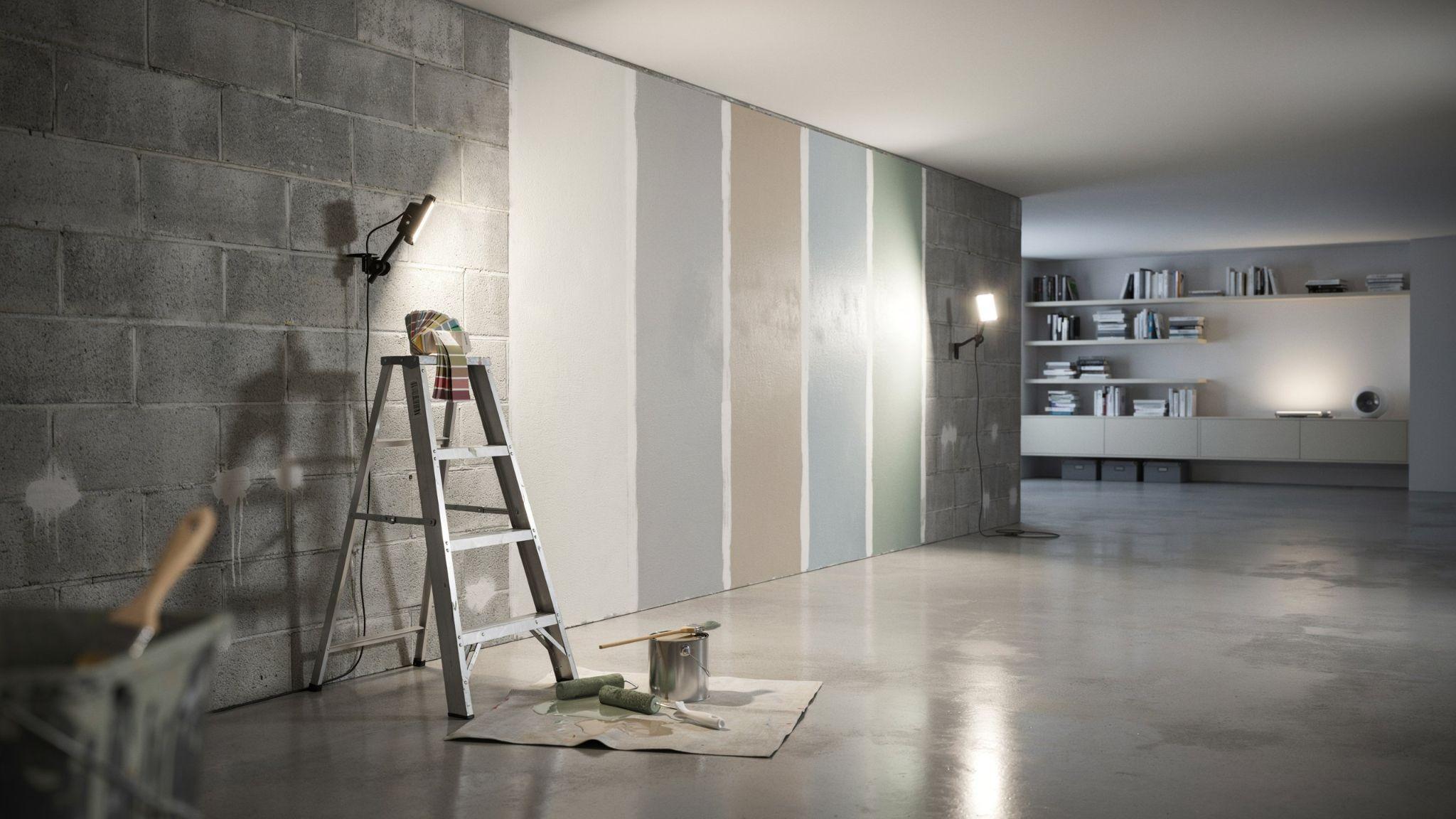 Modern basement interior showing paint color selection process with multiple wall swatches, lighting comparison, and decorating tools to choose the best basement paint colors.