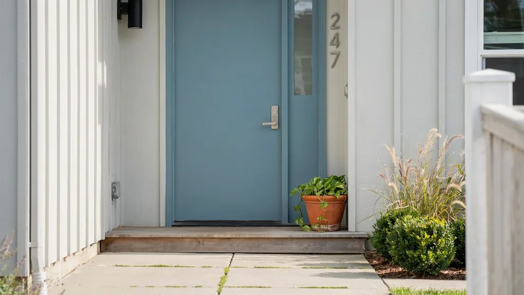 Teal front door on modern home exterior adding a refreshing and trendy look, balanced with surrounding greenery and stylish design elements.