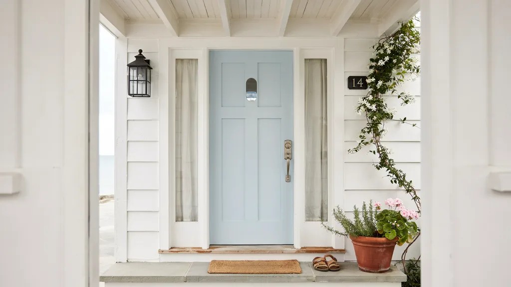 Light blue front door with white trim on coastal-style home, creating a fresh, airy, and relaxed entrance influenced by beachside living.