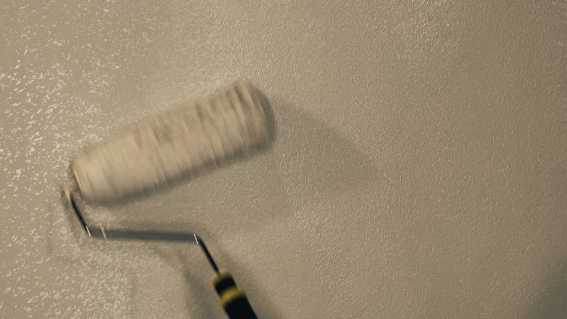 A paint roller moves across a wall showing two finishes side by side.