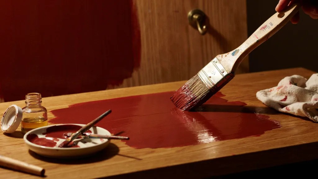 Oil-based paint being brushed onto a surface with a thick, glossy, durable finish.