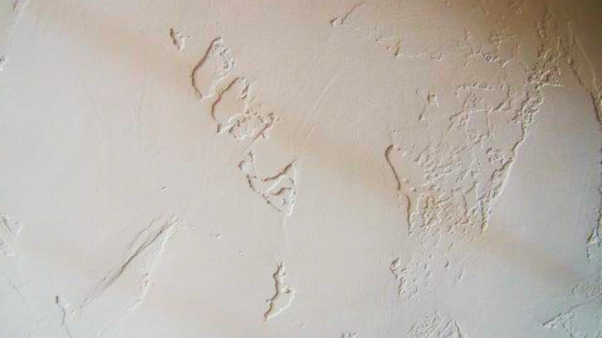Off-white drywall showing skip trowel texture with irregular raised patches and smooth areas.