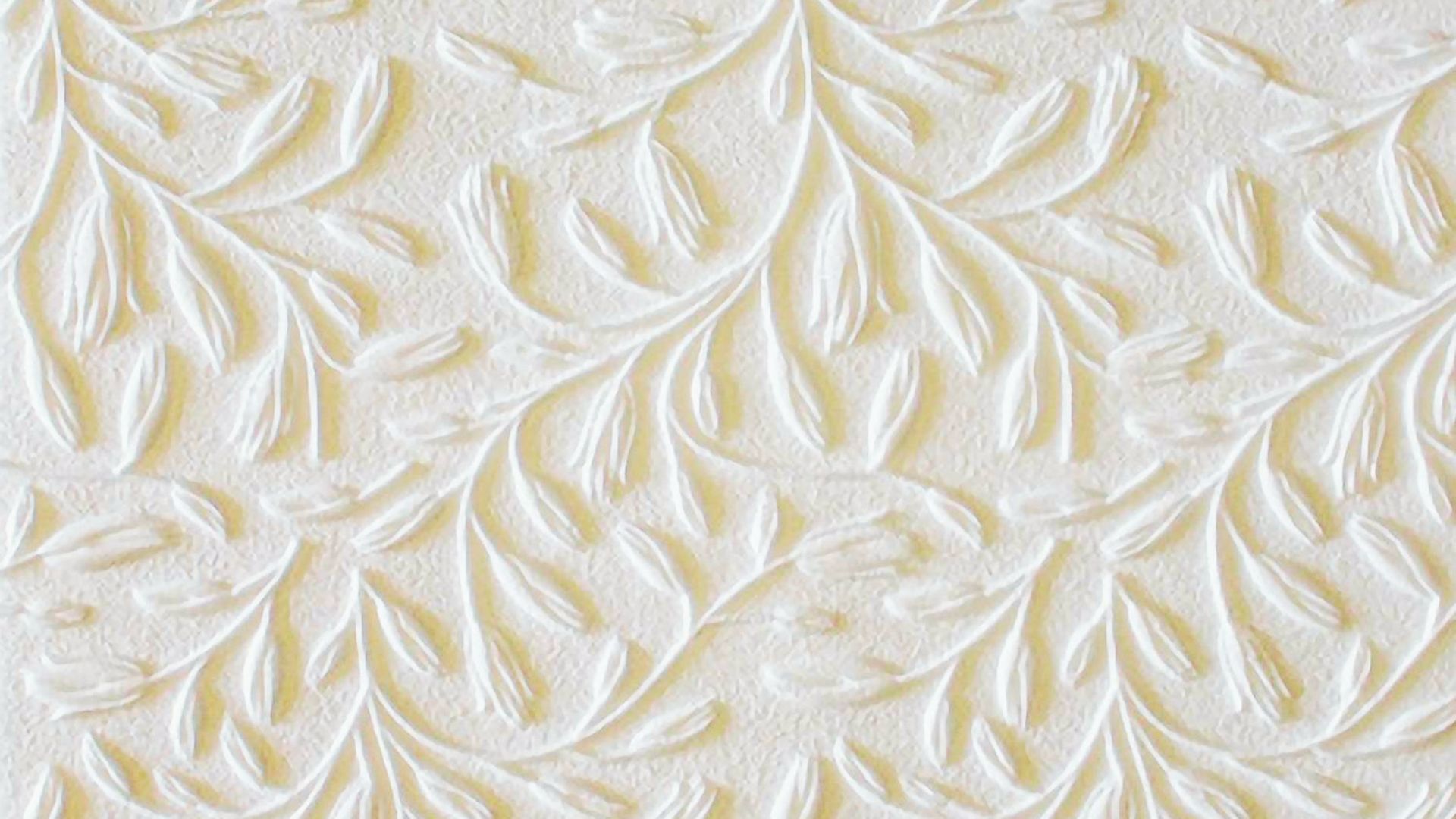 Close-up of white drywall with raised leaf and vine pattern in an embossed texture.