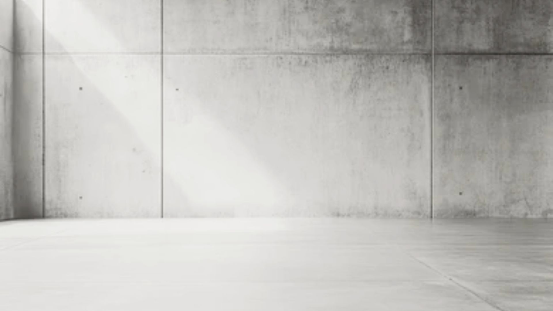 Minimalist concrete-look drywall panels with visible seams in an empty industrial room.