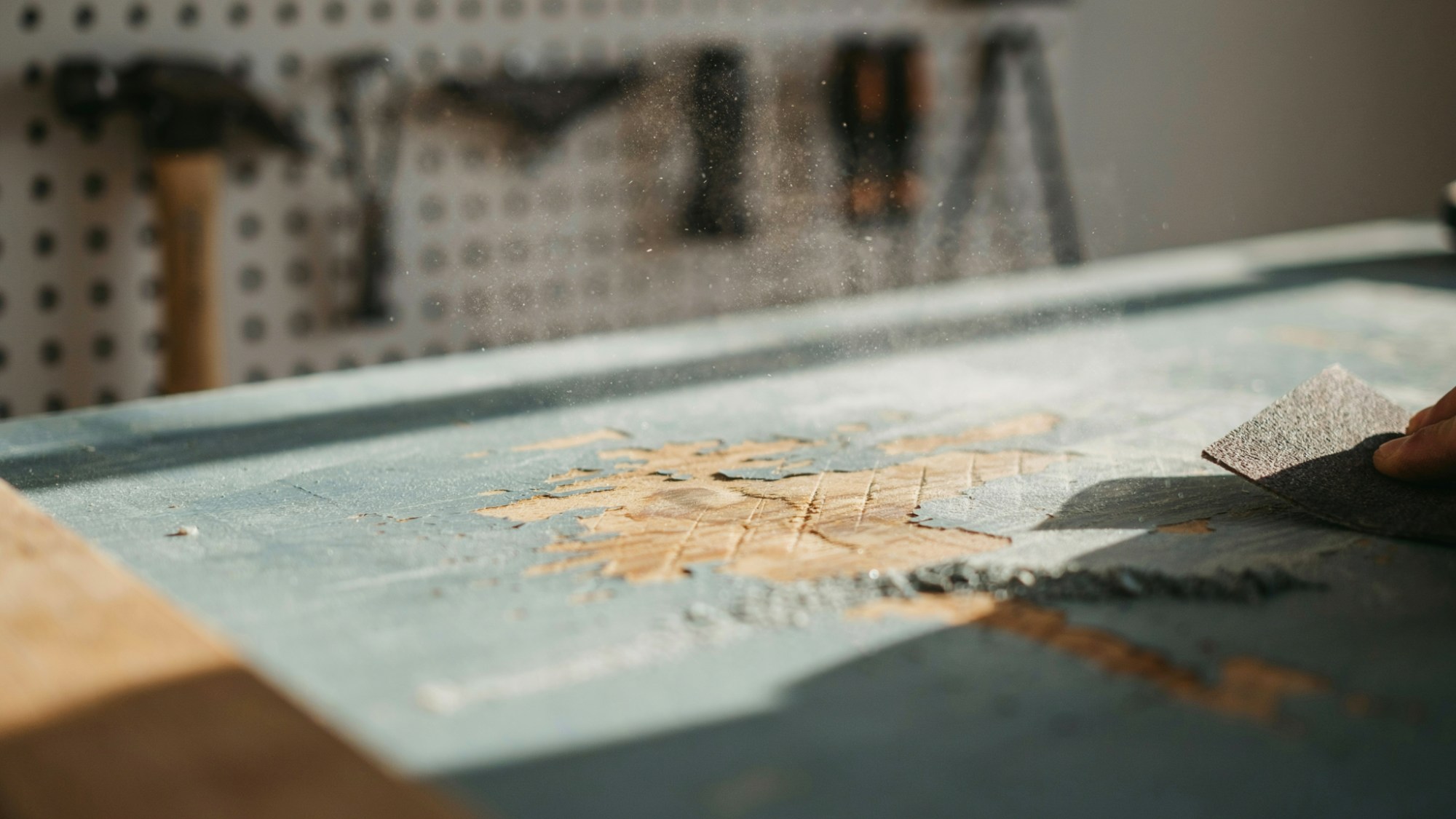 Fine-grit sandpaper smoothing a painted surface before priming and repainting.