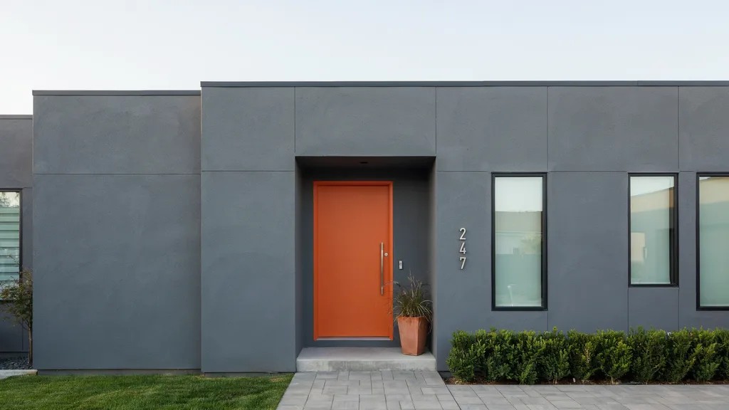 Bright orange front door on modern home exterior creating bold contrast, giving the entrance a creative, energetic, and contemporary edge.