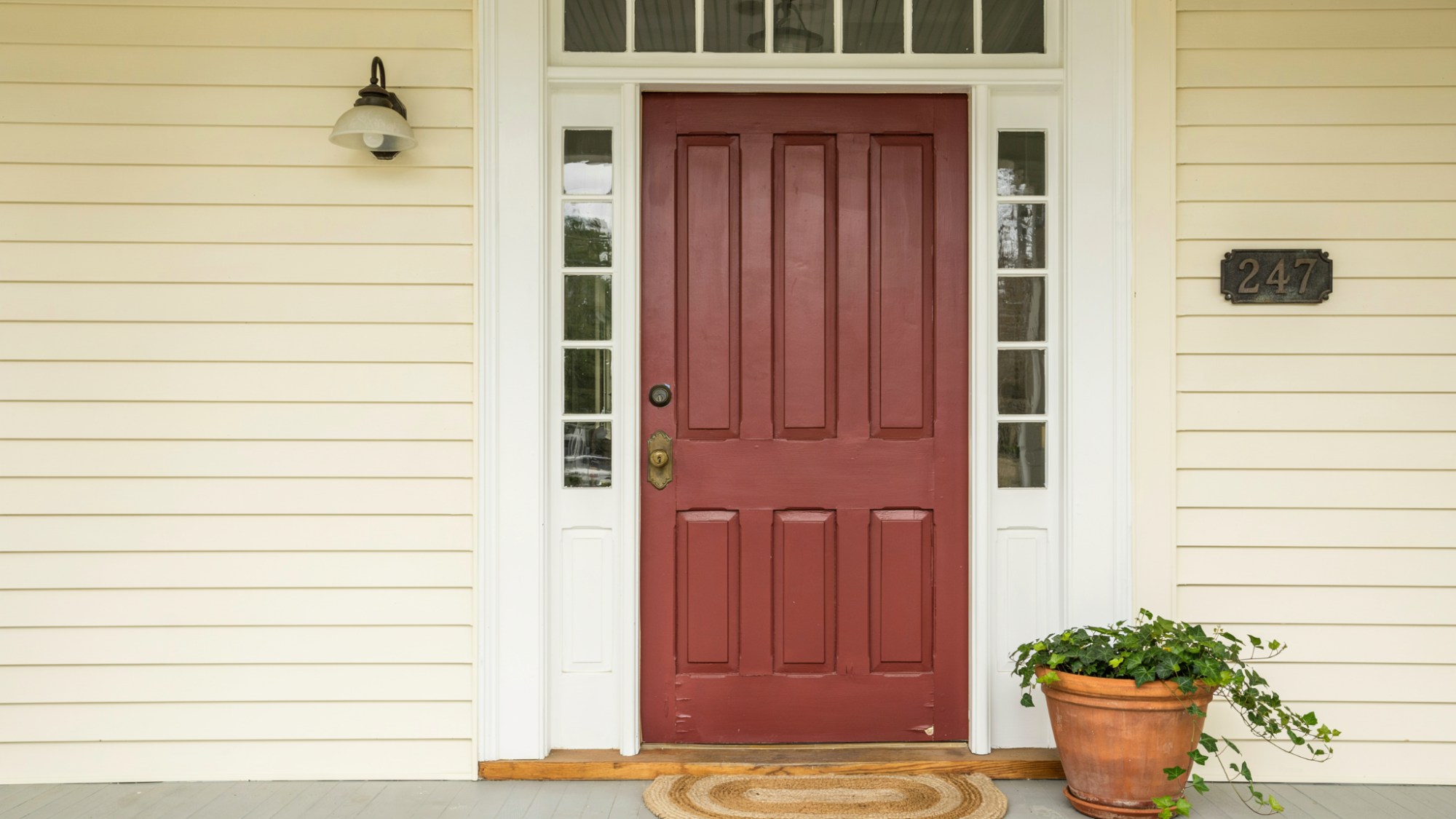 Deep burgundy front door on traditional home with antique hardware, adding warmth, richness, and a luxurious feel to the entrance.