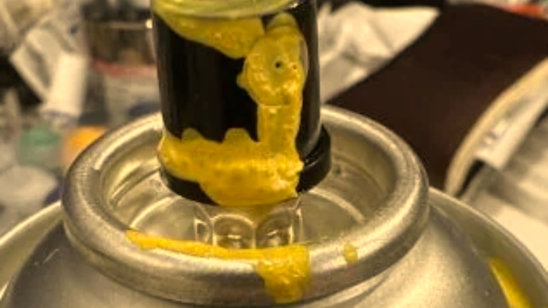 Close view of yellow paint dried around a spray can nozzle.
